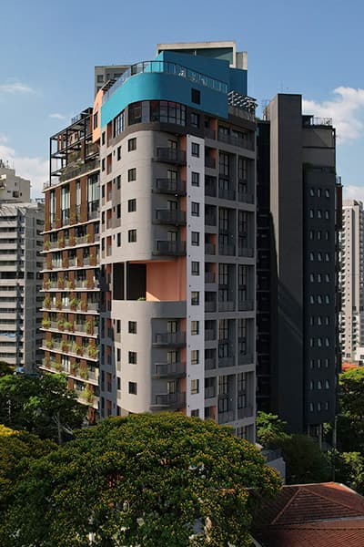 Fachada do edifício em destaque com árvores no entorno e céu azul.